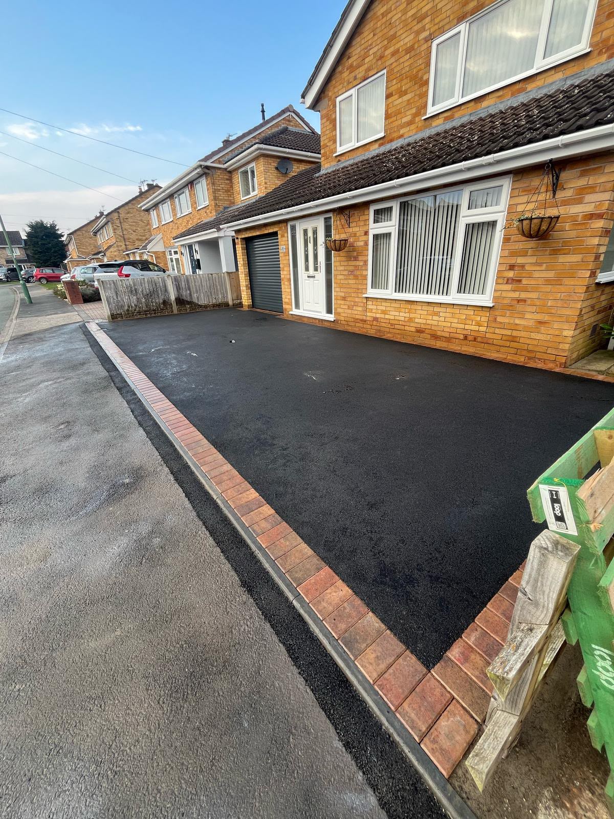 Freshly rolled tarmac driveway with block paving apron and brick edging