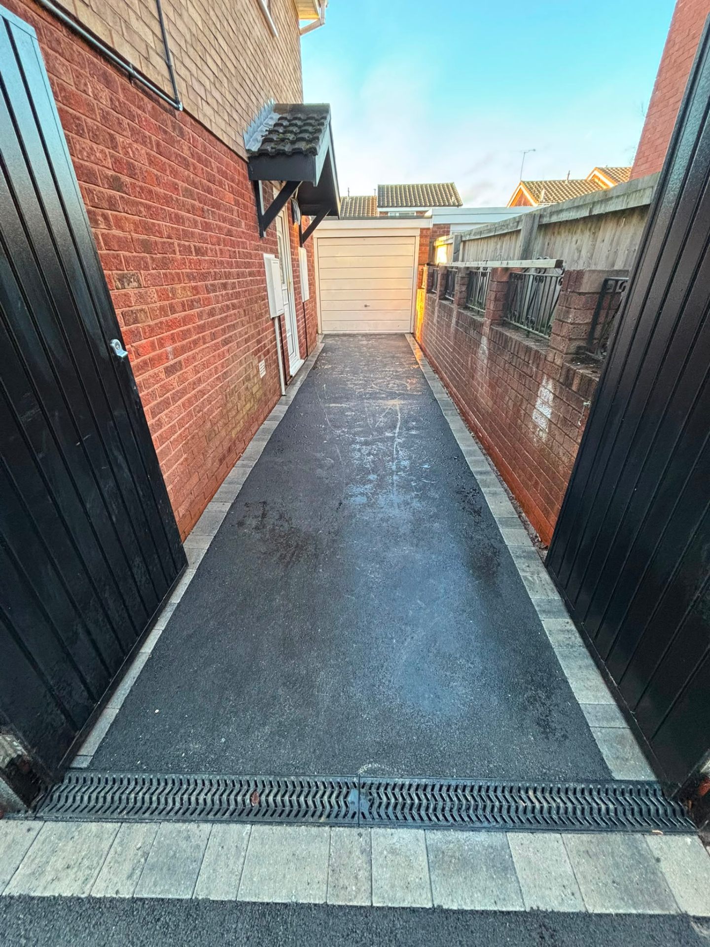Tarmac pathway with brick edging leading to garden