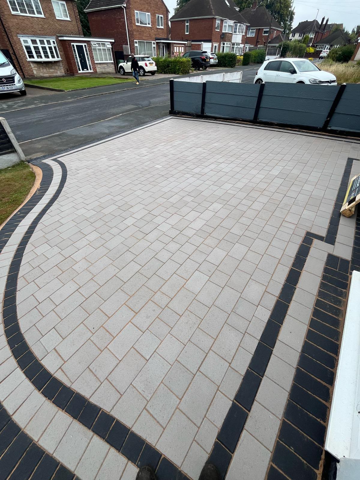 Light grey block paving driveway with dark grey soldier course border and drainage channel