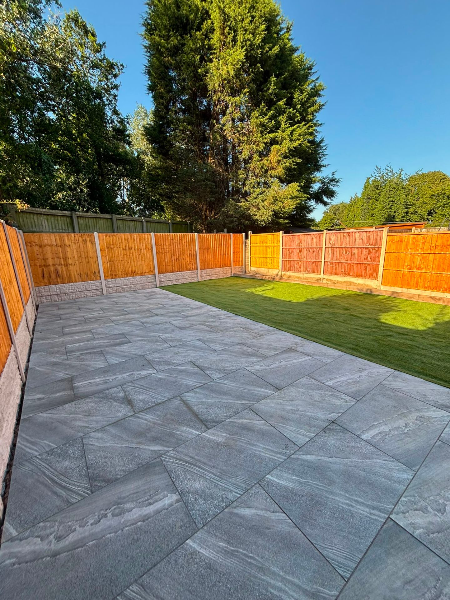 Grey porcelain patio combined with a new artificial grass lawn and timber fencing