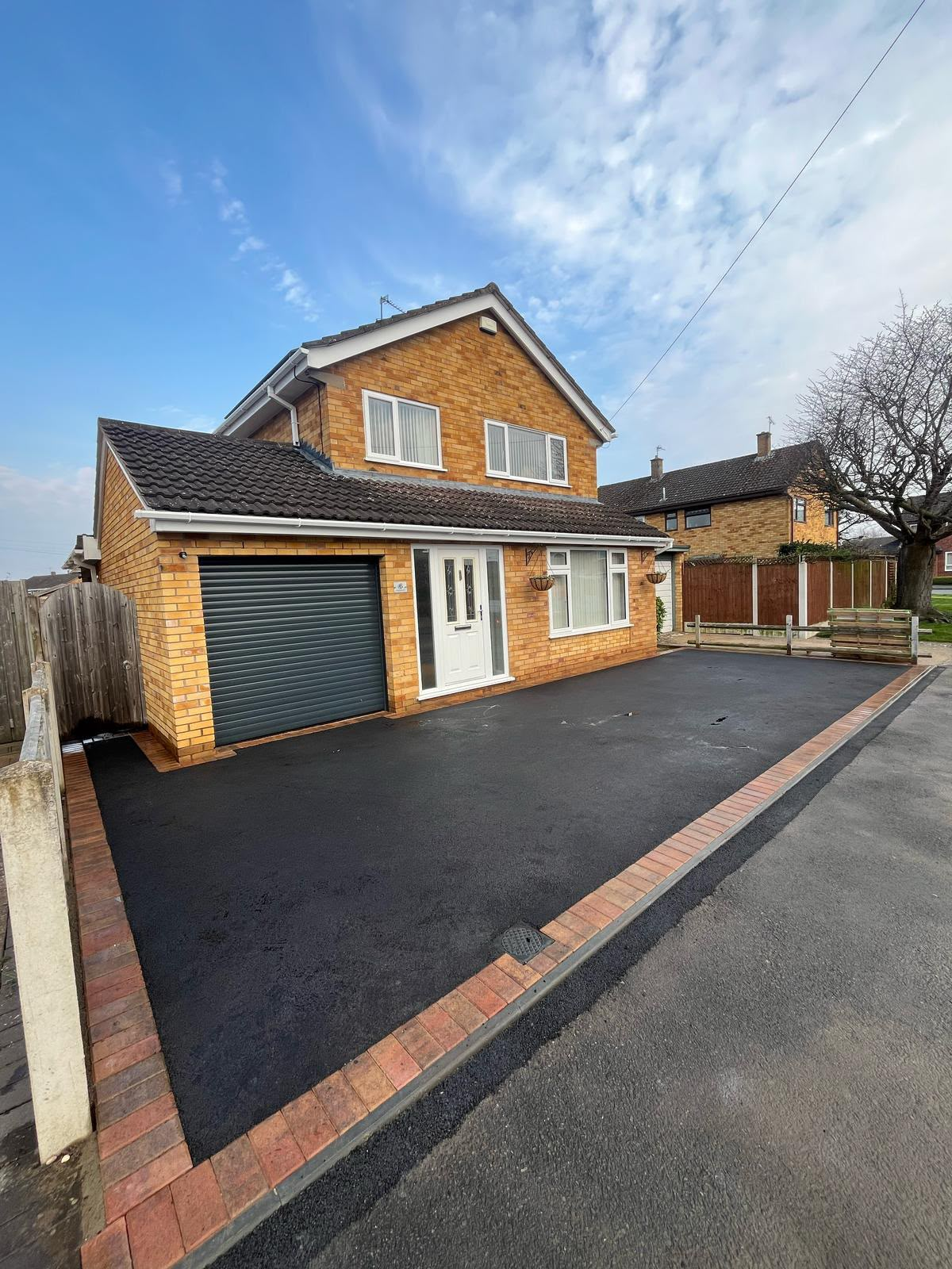 Smooth tarmac driveway with brick paver border to a family home