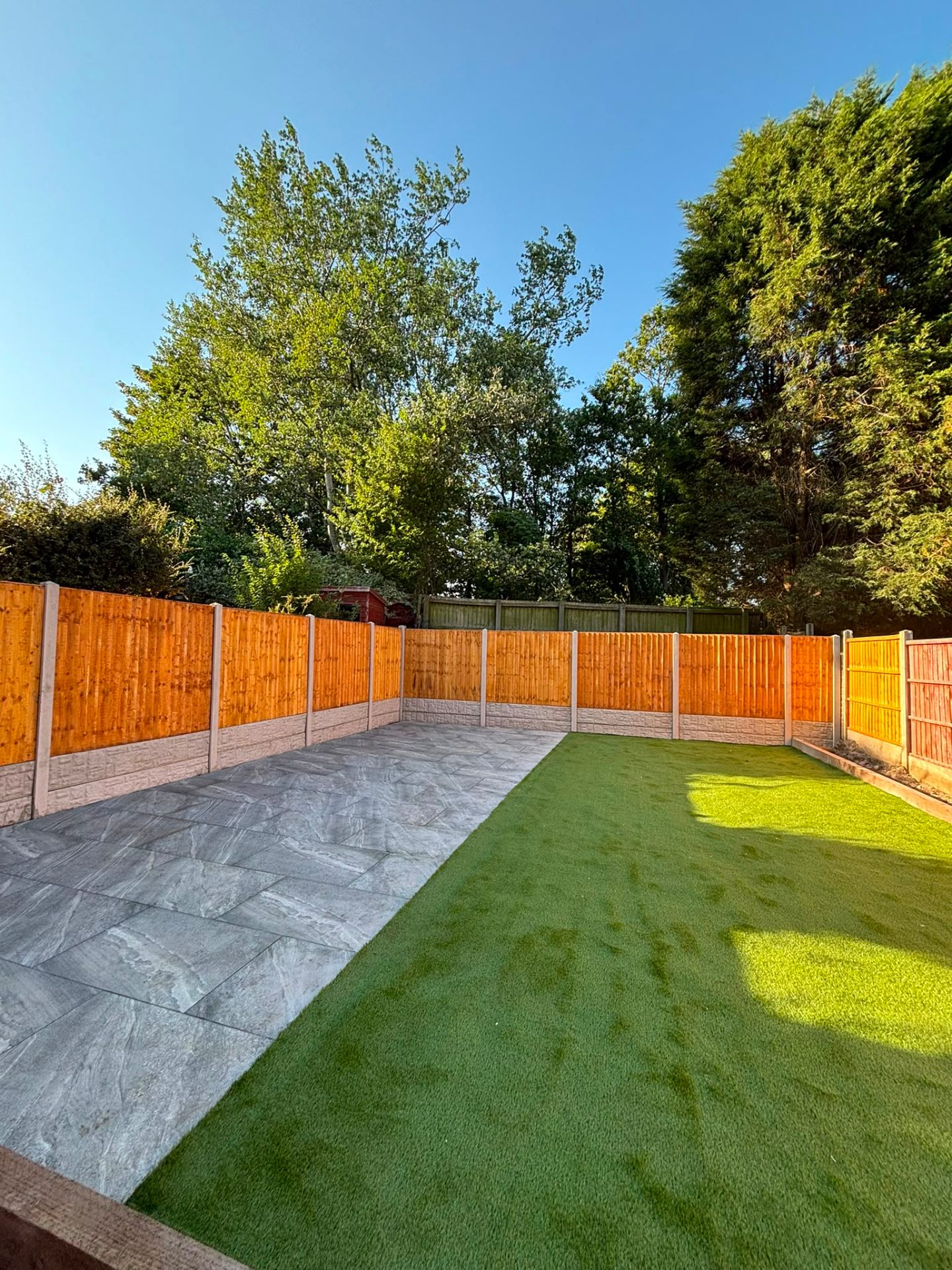 Porcelain patio alongside an artificial grass lawn with fresh timber fencing