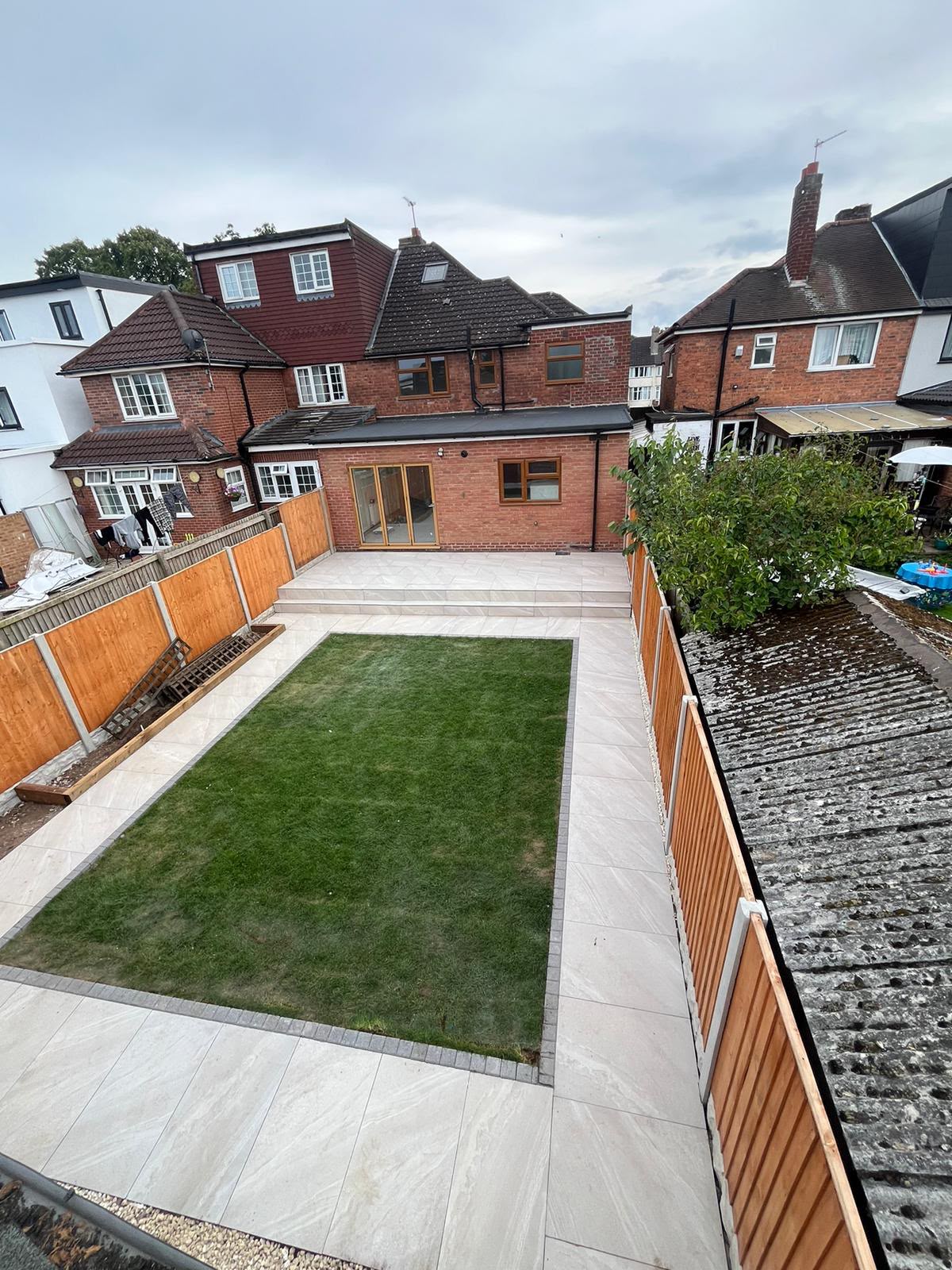 Porcelain patio with charcoal edging viewed from the lawn, West Midlands installation
